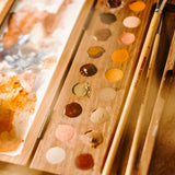 Natural Earth Paint wooden watercolour palette with brush holder features 18 holes for paint, a mixing panel and a brush holder