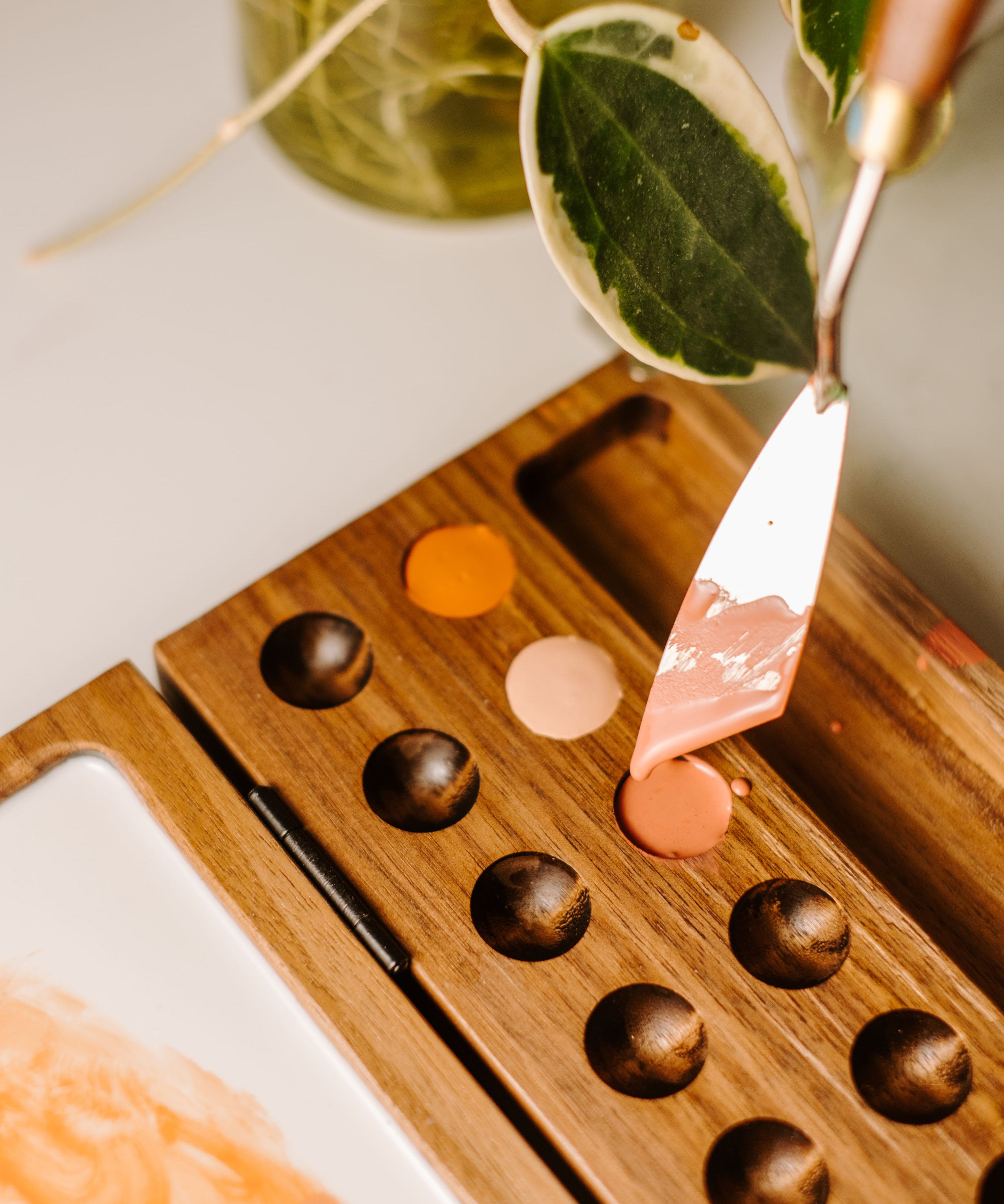 A close up view of the Natural Earth Paint wooden palette showing the palette knife scooping paint from the hole