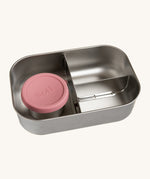 A close up of the One Green Bottle lunchbox showing the 3 different compartments inside separated by a divided. Comes with a little snack pot with a pale pink silicone lid.