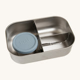 A close up of the One Green Bottle lunchbox in soldier colour. showing the 3 different compartments inside separated by a divided. Comes with a little snack pot with a pale blue silicone lid.