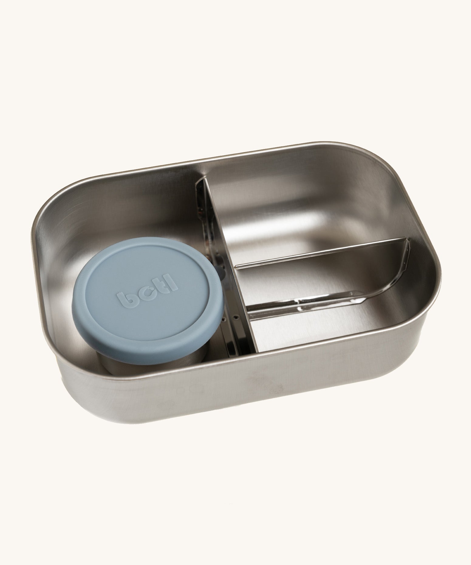 A close up of the One Green Bottle lunchbox in soldier colour. showing the 3 different compartments inside separated by a divided. Comes with a little snack pot with a pale blue silicone lid.