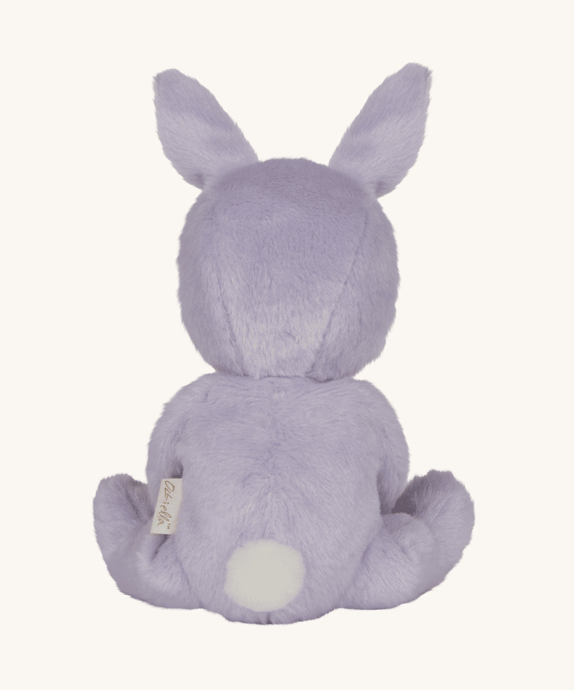 Olli Ella purple coloured Babs Bunny Dinky Dinkum Doll in a seated position facing away from the camera showing the back of the doll. A white fluffy tail can be seen.