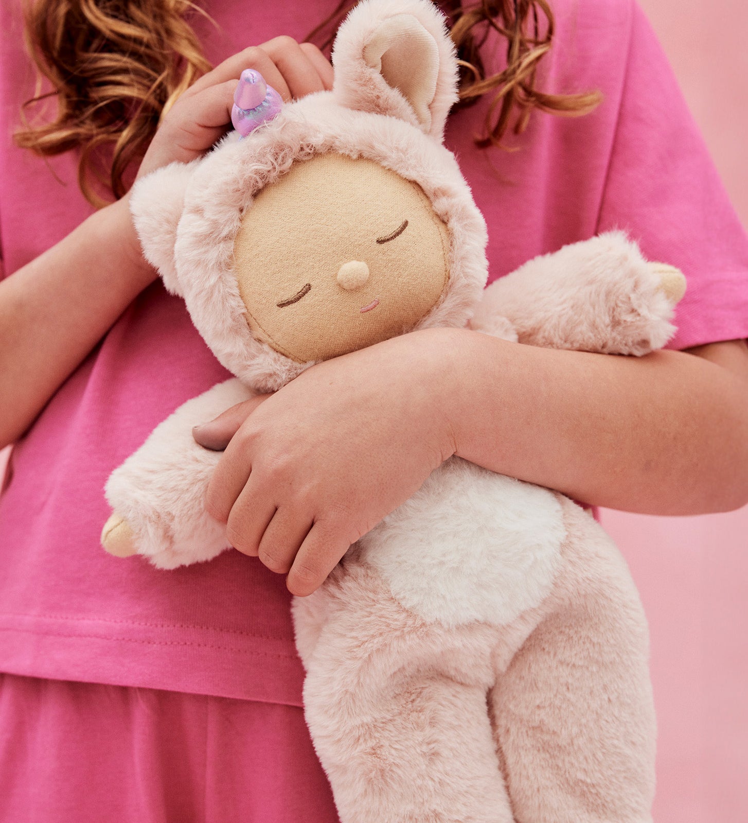 A child holding the pink fluffy Olli Ella dinkum doll
