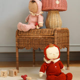 The Olli Ella rattan toadstool lamp with a natural base and a pink mushroom top, on a table with dinkum dolls.
