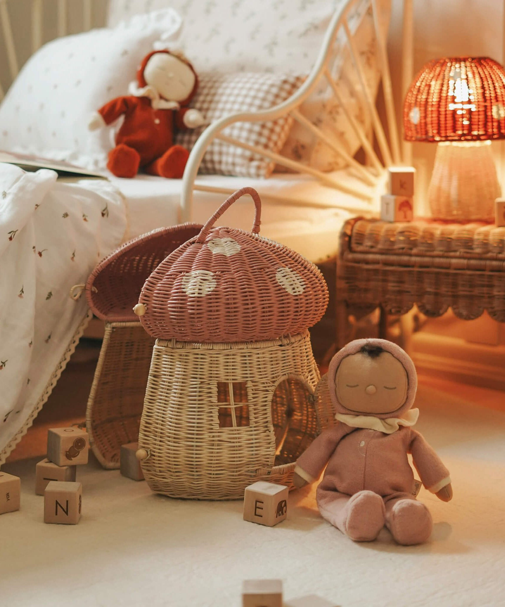 The Olli Ella Dozy Dinkum Doll - Toadstool Pip. It is in a bedroom with a mushroom rattan doll's house basket.