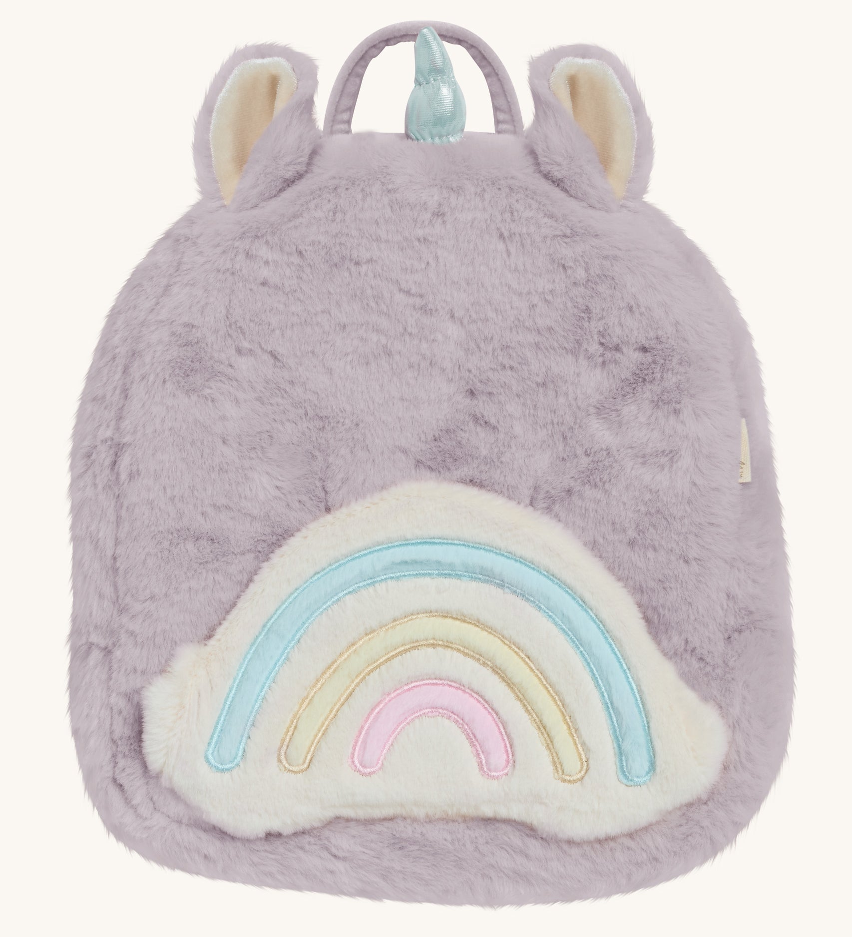 A lilac Olli Ella fluffy unicorn backpack with a rainbow on the front on a cream background.