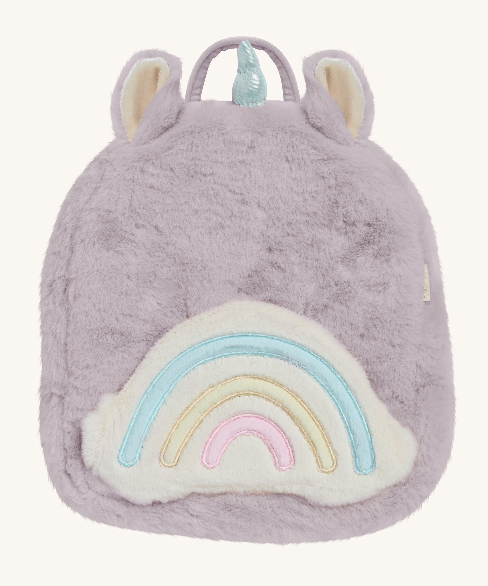 A lilac Olli Ella fluffy unicorn backpack with a rainbow on the front on a cream background.