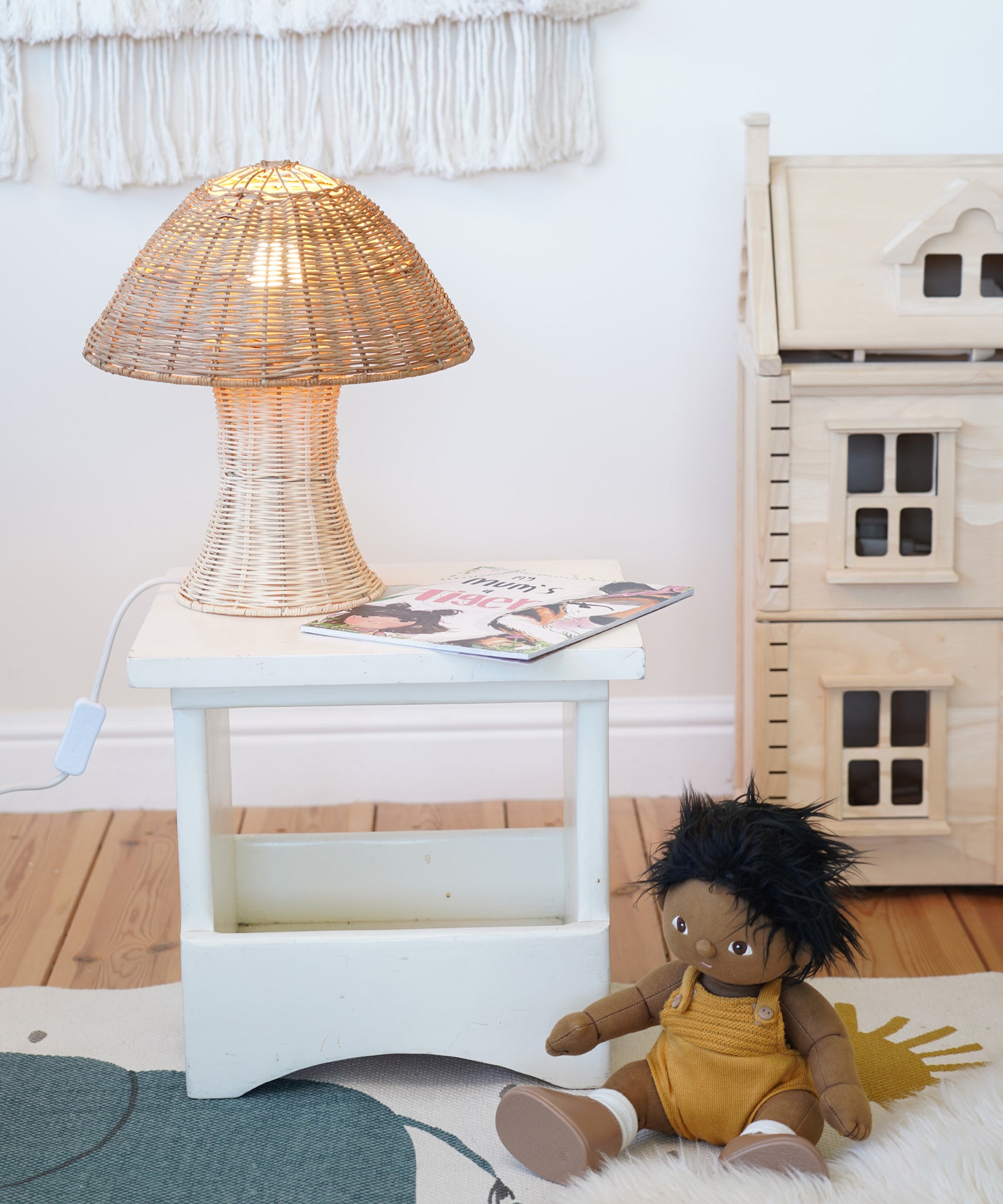 An Olli Ella Natural Rattan Mushroom Lamp placed on a small white square stool.