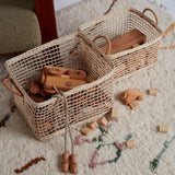2 natural woven olli ella cabouche rattan baskets filled with wooden toys on a white carpet
