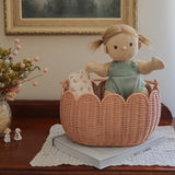 A Dinkum Doll placed in and Olli Ella Seashell Pink Petal Basket.
