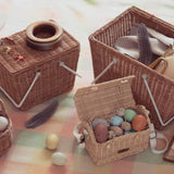 a rattan picnic basket with white handles