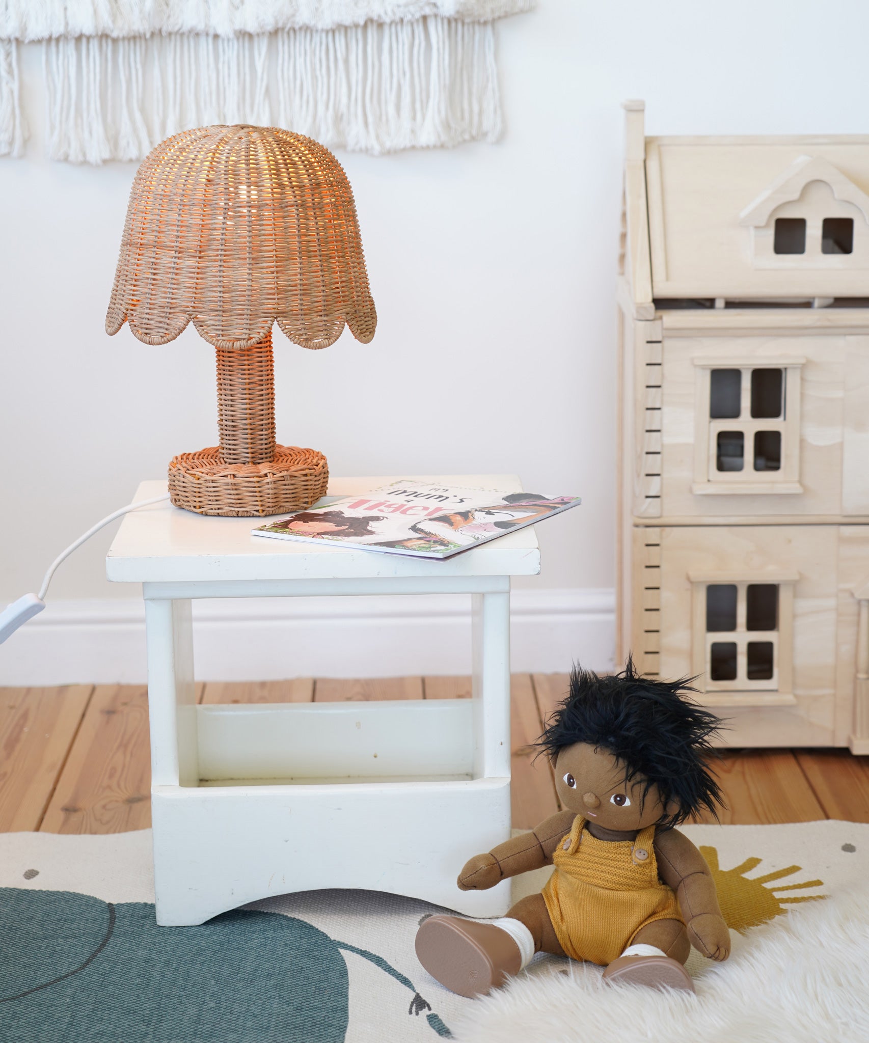 An Olli Ella Rattan Petal Lamp placed on a white bedside table.