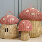 The Olli Ella rattan toadstool lamp with a natural base and a pink mushroom top, with two toadstool baskets in the same style.