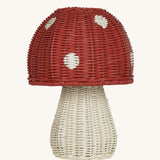 The Olli Ella rattan toadstool lamp with a white base and a red mushroom top.