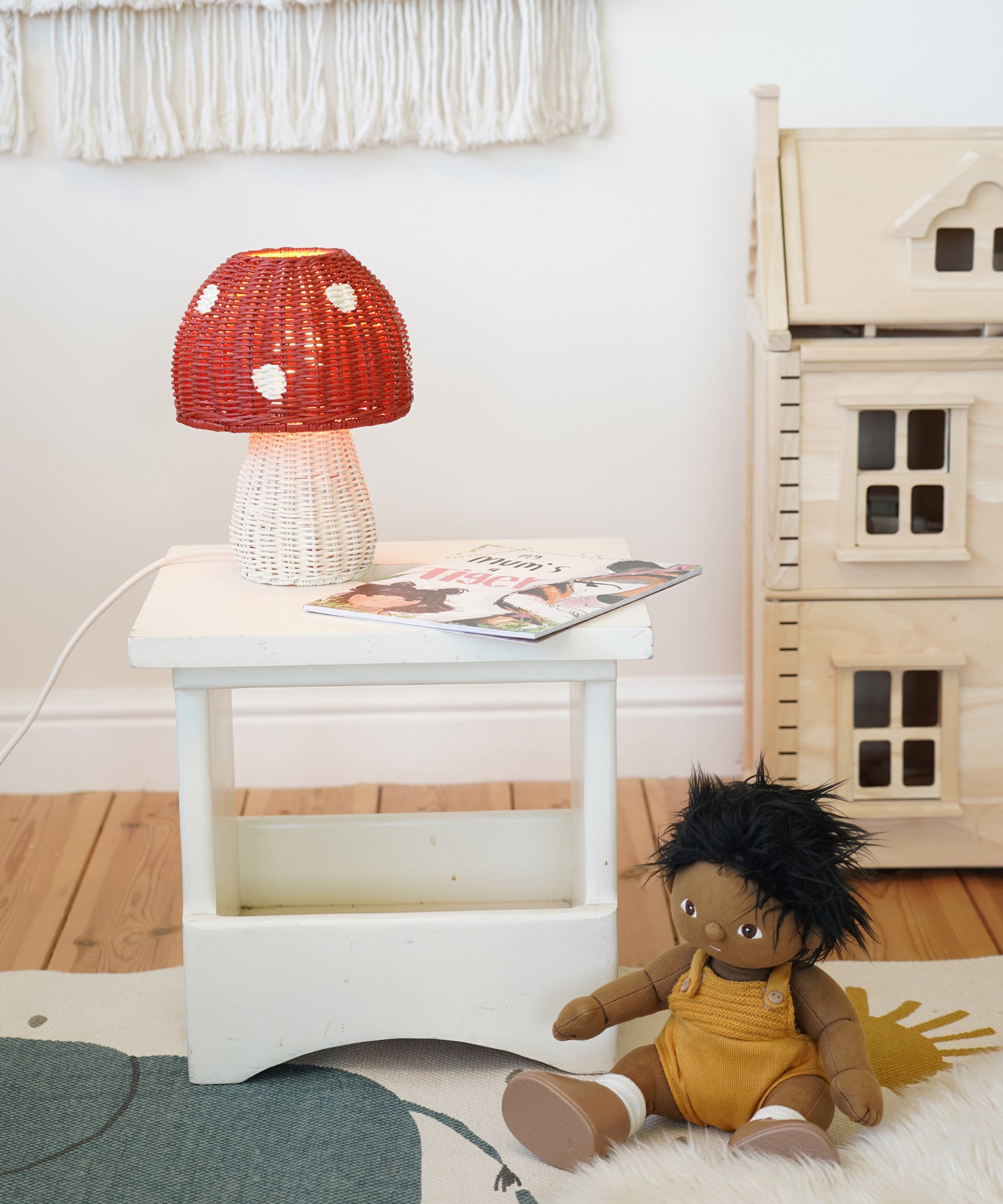 An Olli Ella Rattan Toadstool Lamp placed on a square wooden stool.