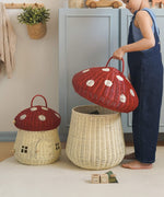A child taking off the spotty mushroom lid of the red Olli Ella toadstool basket.