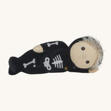 Olli Ella Scully Skeleton Dinky Dinkum Doll soft toy laying on it's side. The doll features glow in the dark bone details on the front along with a small embroidered rainbow on the chest. These soft toys are part of Olli Ella's Halloween collection available here at Babipur.