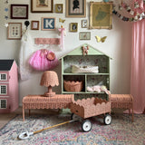 An Olli Ella Rattan Petal Lamp in the seashell pink colourway pictured alonside other pieces from the seashell pink rattan collection.