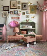 An Olli Ella Rattan Petal Lamp in the seashell pink colourway pictured alonside other pieces from the seashell pink rattan collection.