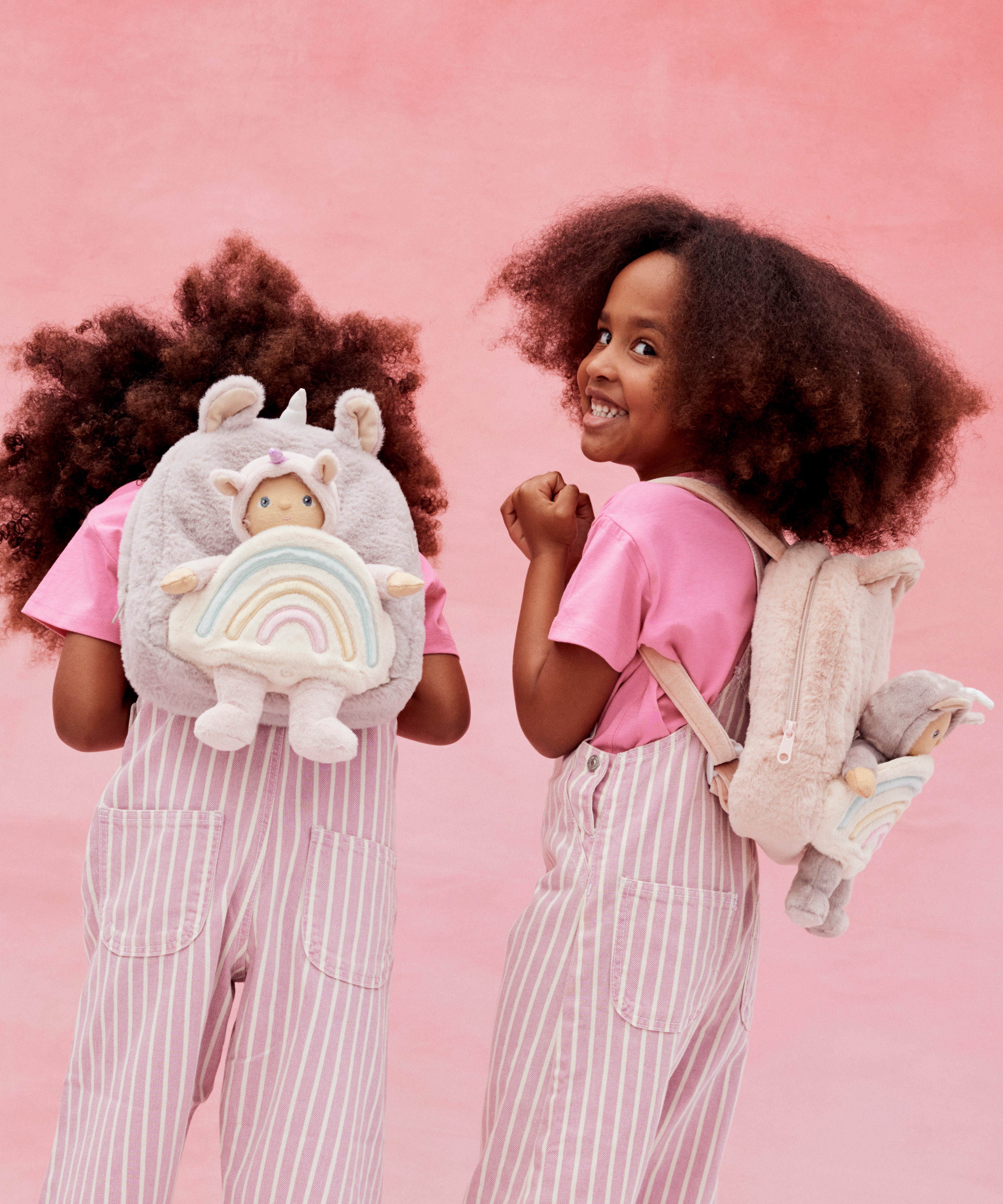 2 kids wearing the pink and lilac Olli Ella backpacks with dinky dinkum dolls on the back.