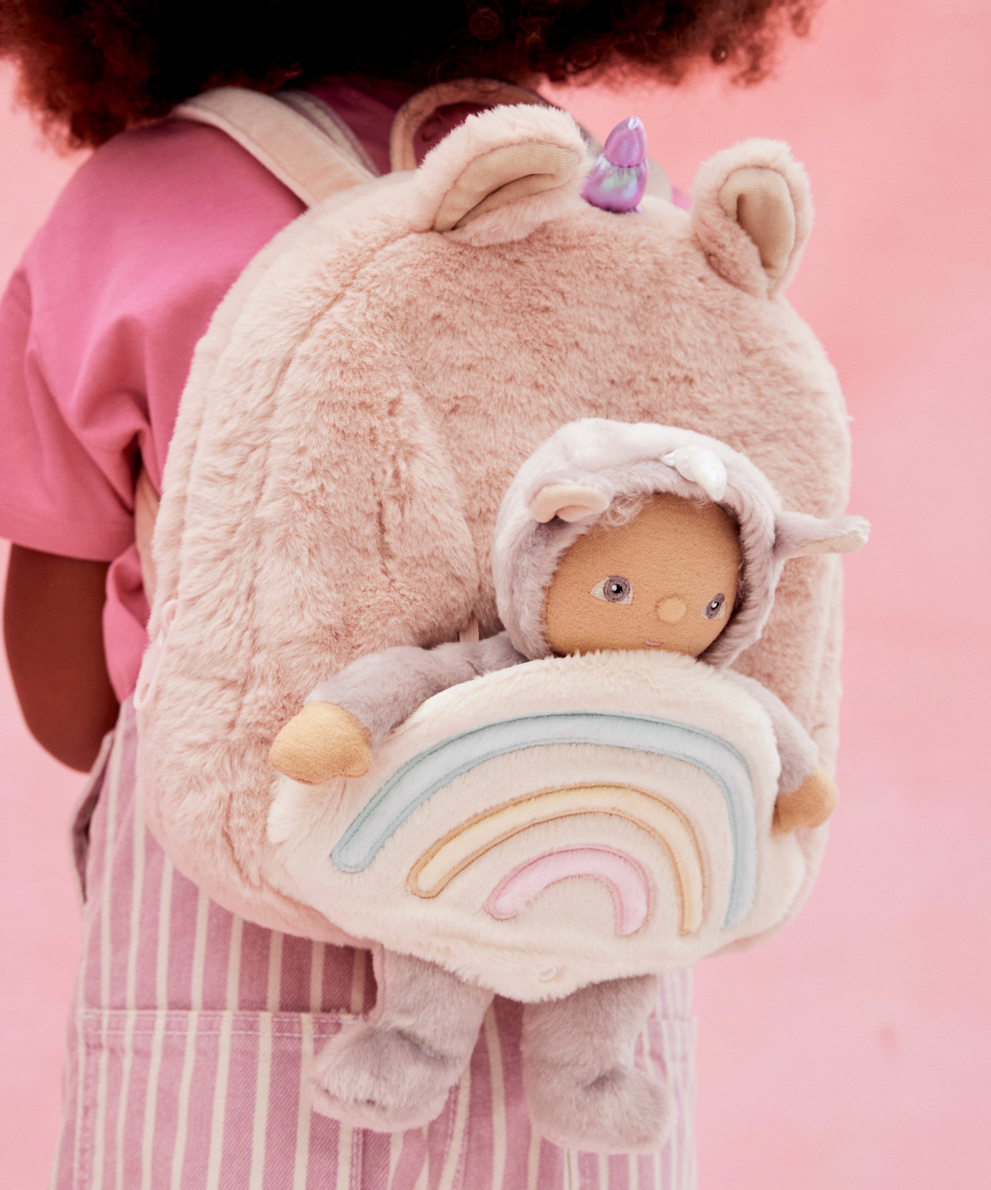 A close up of the pink fluffy backpack with a dinky dinkum doll sitting inside the bag