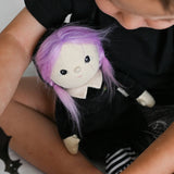 A child holding the Olli Ella Willa Witch Dinky Dinkum Doll. A witch with a black outfit and matching hat with glow in the dark features on the striped tights, collar and stars on the hat. These soft toys are part of Olli Ella's Halloween collection available here at Babipur.
