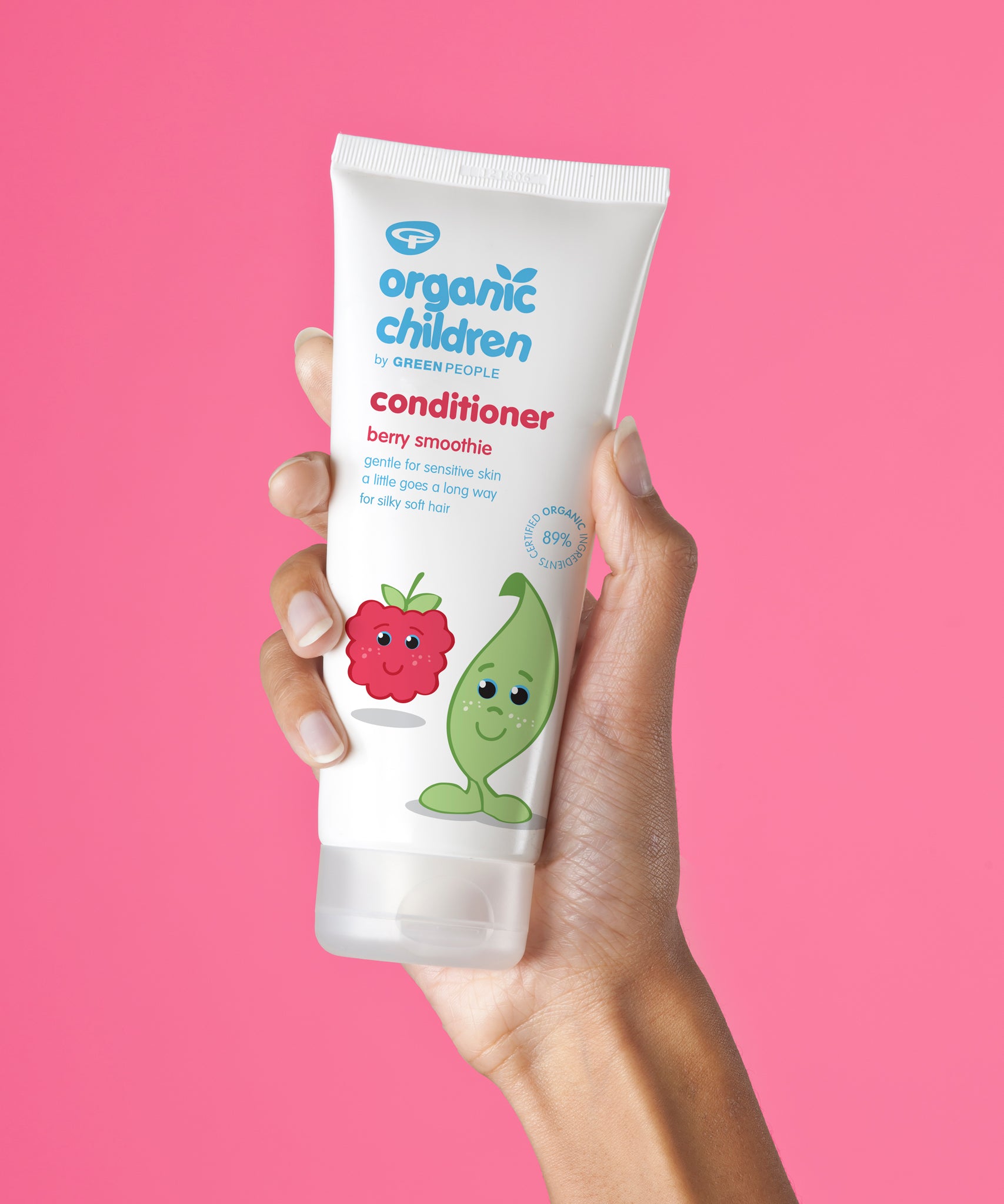 Organic Children Berry Smoothie Conditioner in an adult's hand pictured against a bright pink background.