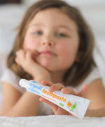 A child holding on a tube of Organic Children Toothpaste Mandarin & Aloe Vera with Fluoride.
