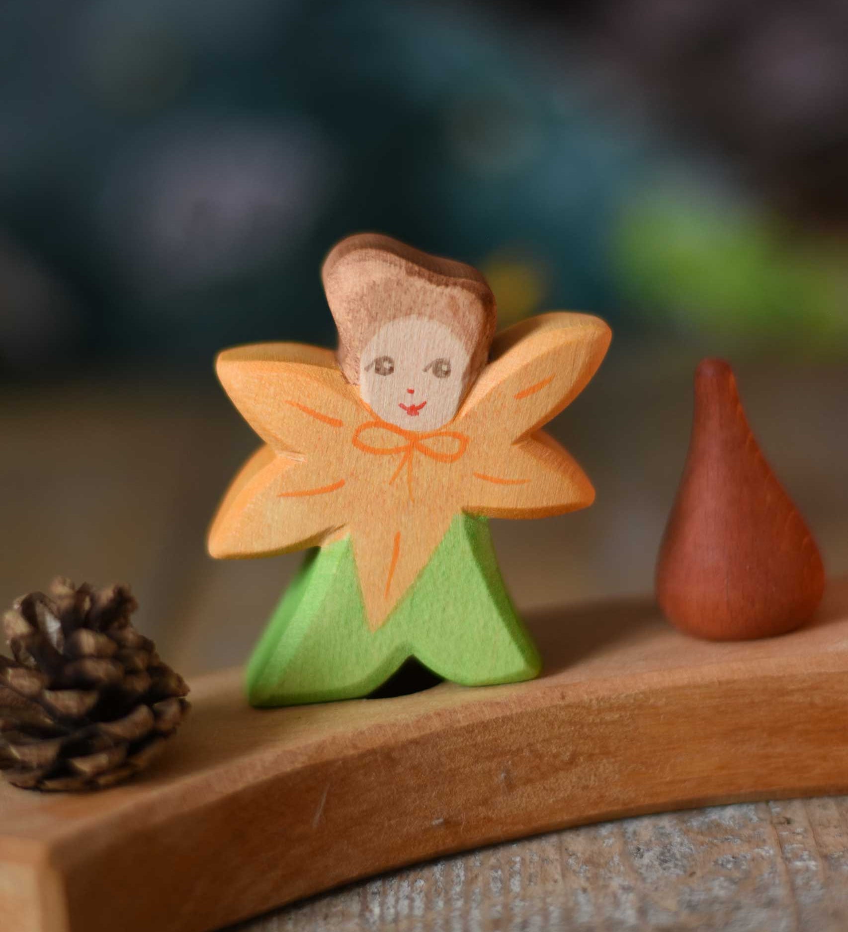 The Ostheimer hand made and hand painted wooden Calendula Flower Child figure toy placed on a Grimm's natural celebration ring.