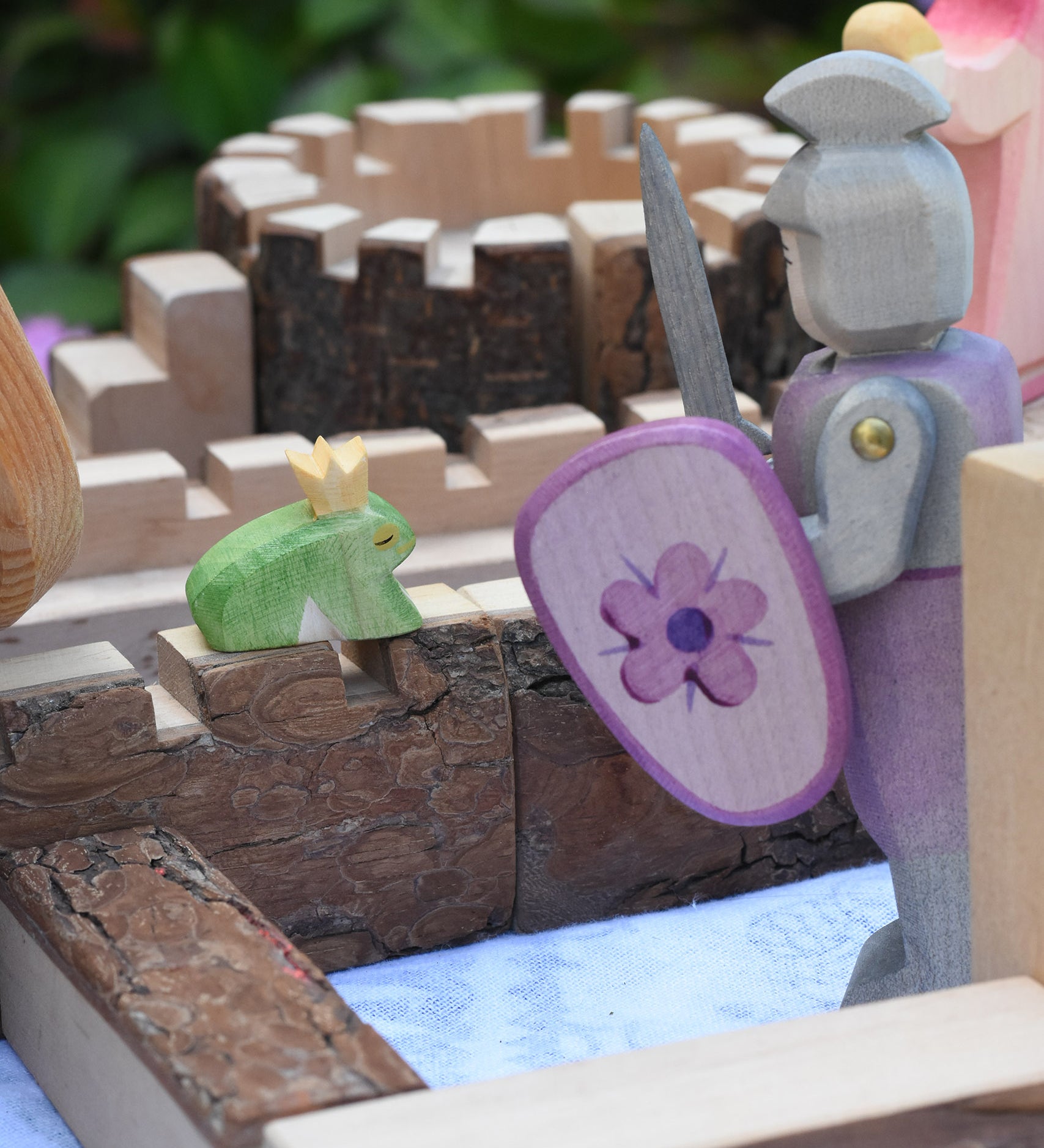 An Ostheimer fog prince wooden toy figure placed on the walls of a Magic Wood castle. The Ostheimer pink knight is standing to one side.  These wooden figures are part of a large range of expertly hand crafted wooden toys here at Babipur.