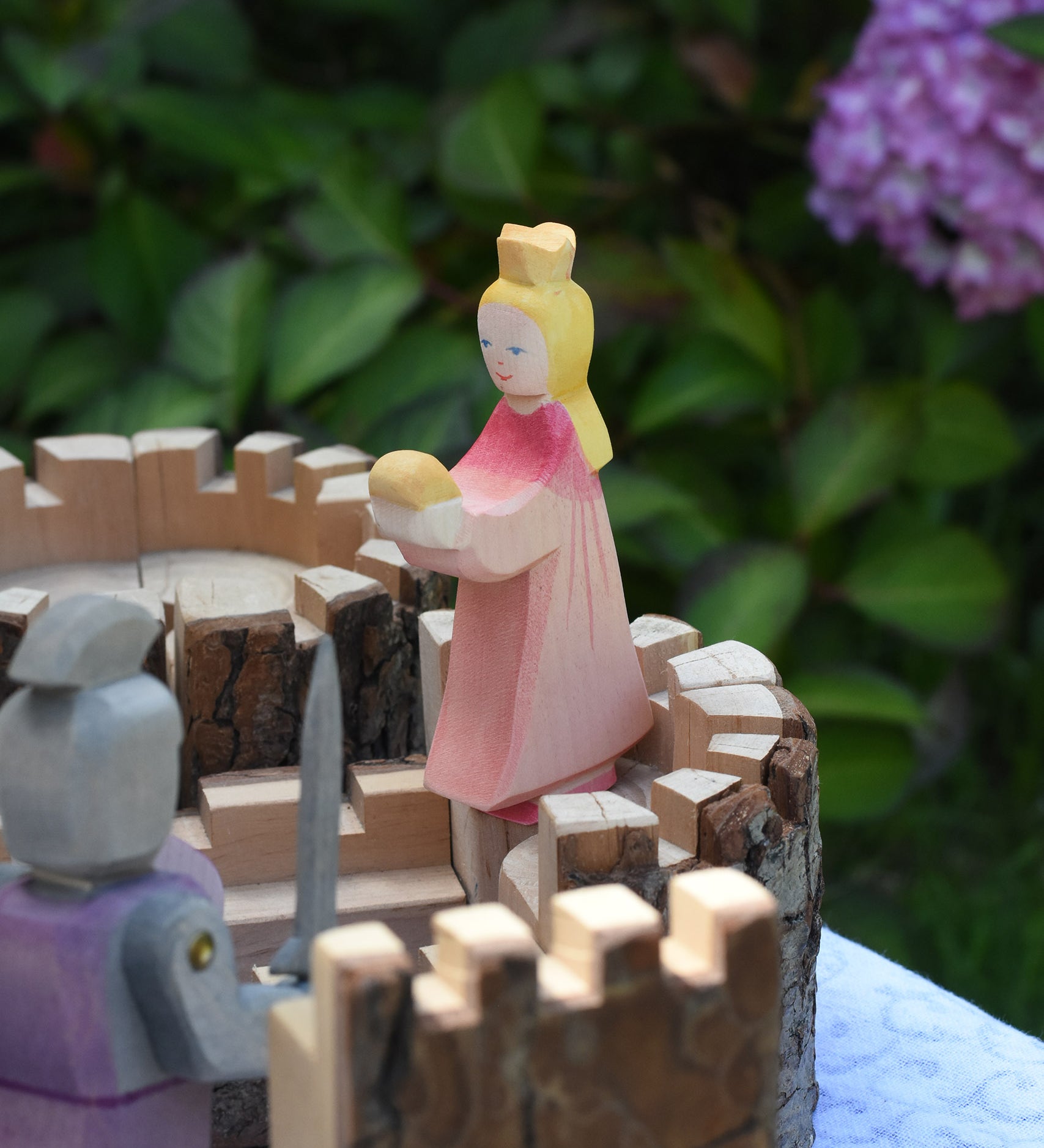 An Ostheimer pink princess for frog prince placed on the turret of a Magic Wood castle. This wooden figure is part of a large range of expertly hand crafted, Waldorf inspired, wooden toys here at Babipur.