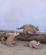 Three Ostheimer wooden toy raccoon figures placed in a simple small world play scene. Check out our full range of expertly crafted wooden toy figures and scenery here at Babipur.