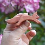 An Ostheimer running red squirrel figure shown in an adult's hand for scale. Check out our full range of expertly crafted wooden toy figures and scenery here at Babipur.