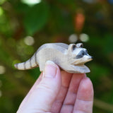 A small Ostheimer raccoon shown in an adult's hand for scale. Check out our full range of expertly crafted wooden toy figures and scenery here at Babipur.