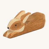 A small brown spotted rabbit resting on a cream background.