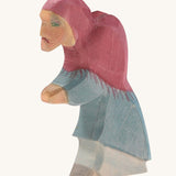 A wooden Ostheimer witch figure wearing a blue outfit and a purple hood on a cream background.