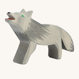 A wooden howling Ostheimer grey wolf figure on a cream background.