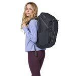 A side view of a woman wearing The Patagonia Black Hole Pack 32 litre capacity backpack in smolder slate-blue