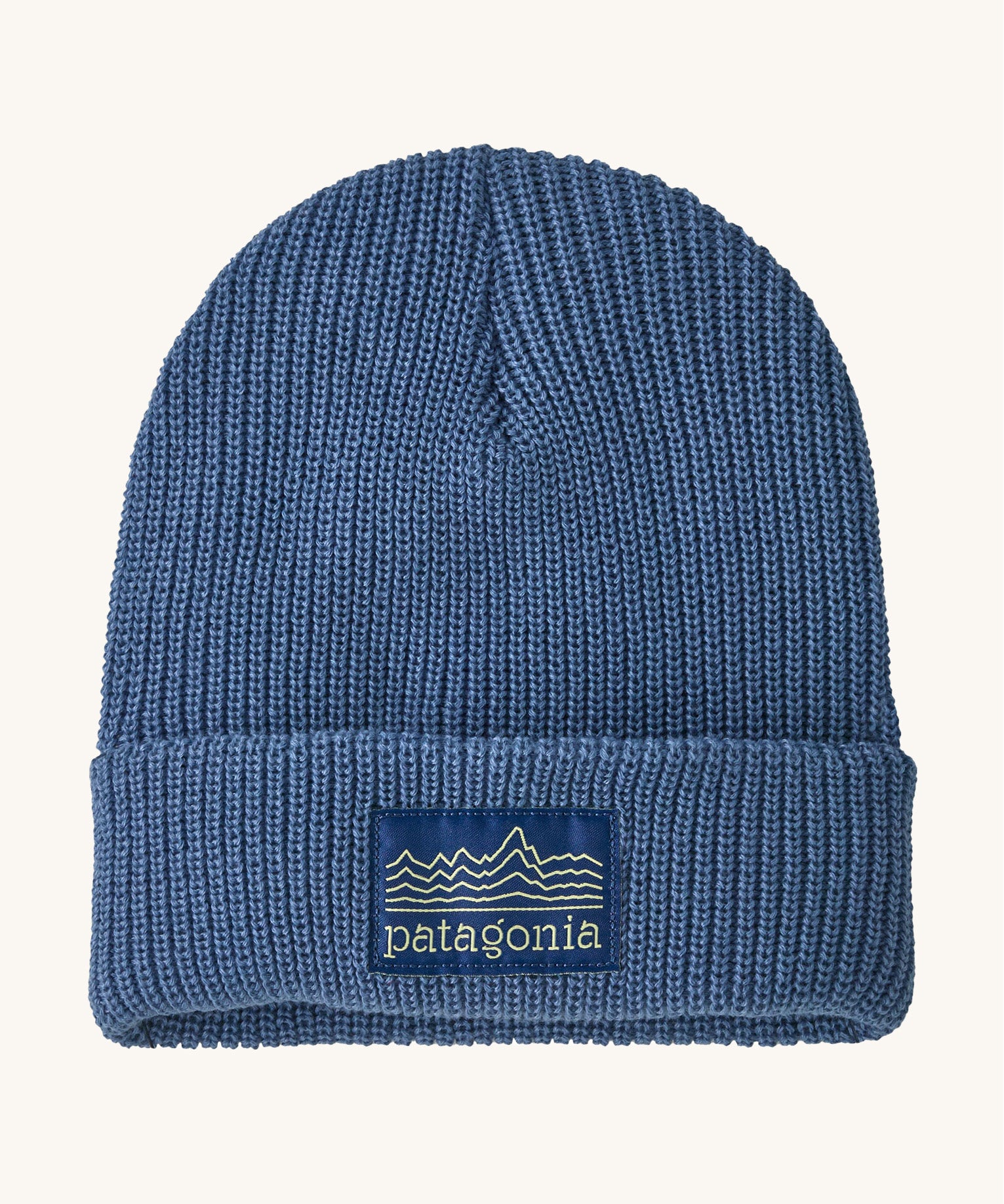 Patagonia kids beanie. A ribbed style hat in blue with the pastel yellow pencil style logo patch stitched on the turned up brim.