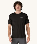 A man wearing the Patagonia Men's Capilene Cool Merino Graphic Shirt with a Heritage Header design in Black.
