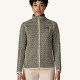A woman wearing the Patagonia Women's Better Sweater Jacket with a scales pattern. The front zip is fully closed. We have a wide selection of Patagonia adults and children's clothing here at Babipur.