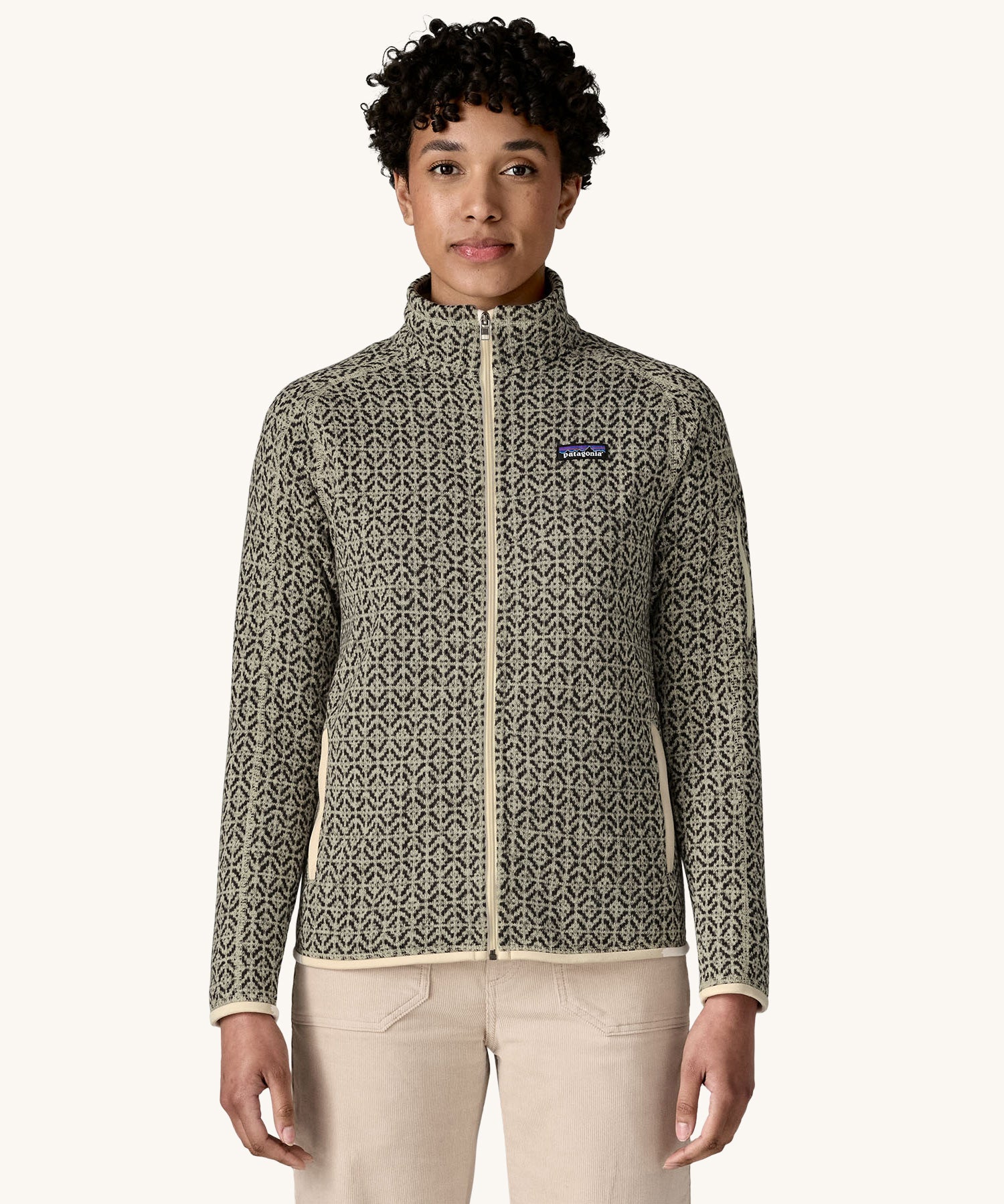 A woman wearing the Patagonia Women's Better Sweater Jacket with a scales pattern. The front zip is fully closed. We have a wide selection of Patagonia adults and children's clothing here at Babipur.