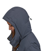 A side profile view close up of a person wearing the Patagonia Women's Downdrift Parka in Pine Smolder Blue showing the hood up