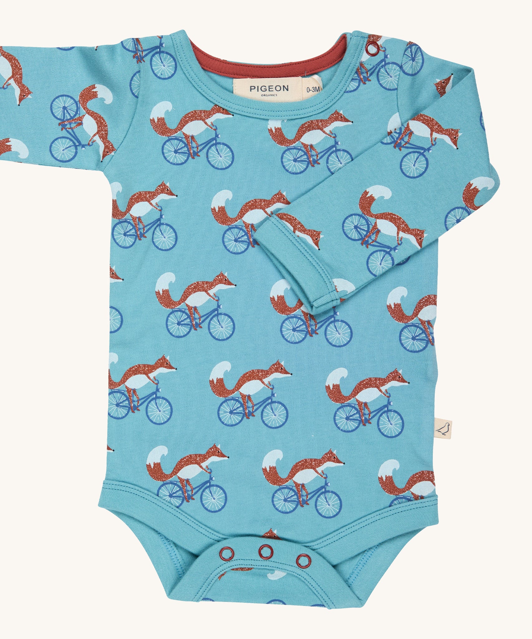 Pigeon Organics Cycling fox body - GOTS organic cotton turquoise baby body with long sleeves and popper fasteners at the crotch. Features multiple prints of a fox riding a blue bike.