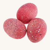 3 wooden speckled pink dinosaur eggs on a cream background