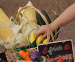 Child's hand reaching for corn on the cob paly food from the Plan Toys Wooden Vegetable Produce Set.