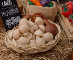 Wooden toy mushrooms from the Plan Toys Produce Set - a set of vegetable play food - in a rattan basket.