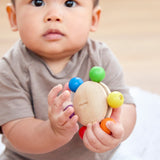 A baby grasping the Plan Toys Wooden Pull & Grasp Toy.