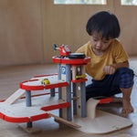 A child playing with the PlanToys Helicopter, the child has placed in on the helipad of the PlanToys parking garage.