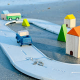 A Plan Toys Rubber Road and Rail Set placed on sand with PlanToys vehicles on.